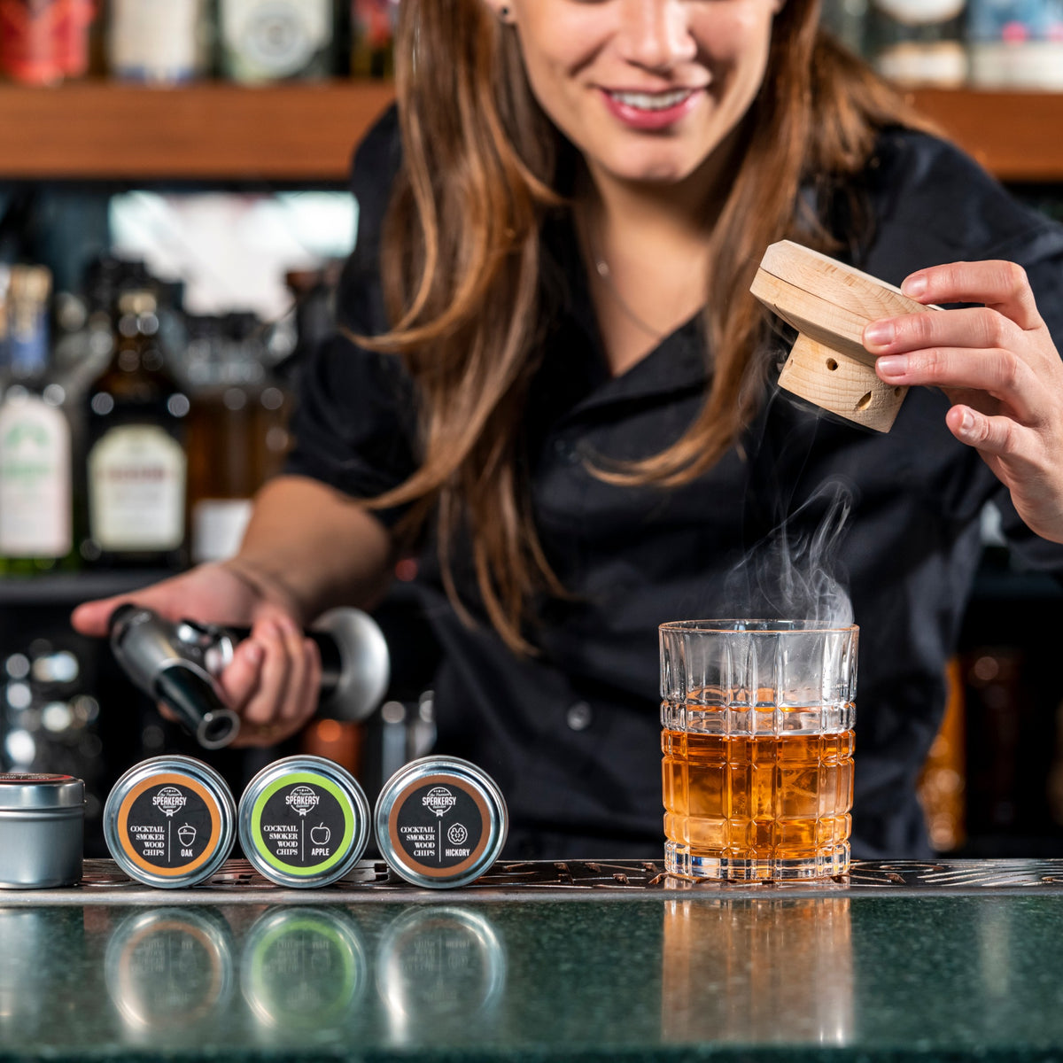 Bartender rookt een cocktail af met rookchips achter de bar